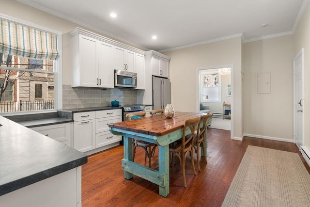 kitchen featuring dark countertops, dark wood-style floors, appliances with stainless steel finishes, and white cabinets