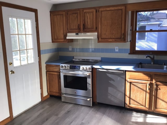 kitchen with backsplash, sink, stainless steel appliances, and light hardwood / wood-style floors