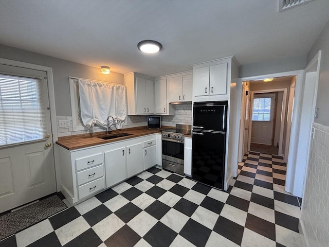 kitchen featuring white cabinetry, sink, tasteful backsplash, stainless steel electric range, and black refrigerator