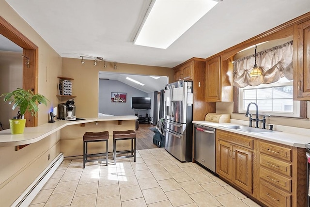 kitchen with pendant lighting, sink, a kitchen breakfast bar, baseboard heating, and stainless steel appliances