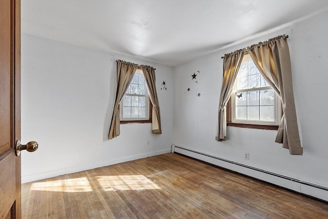 unfurnished room with baseboard heating, plenty of natural light, and hardwood / wood-style flooring