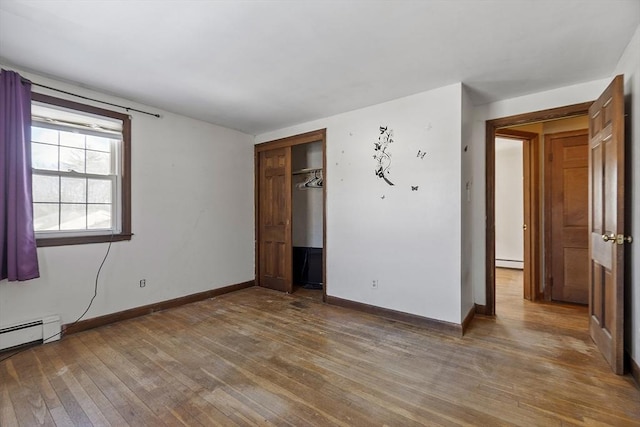 unfurnished bedroom with a baseboard heating unit, dark hardwood / wood-style flooring, and a closet