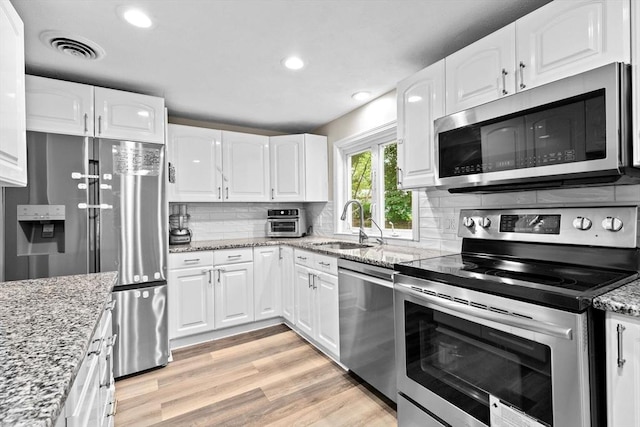15 Leonard Rd, Sharon, MA 02067 - kitchen with stainless steel appliances, white cabinetry, light wood-style flooring, tasteful backsplash, and recessed lighting