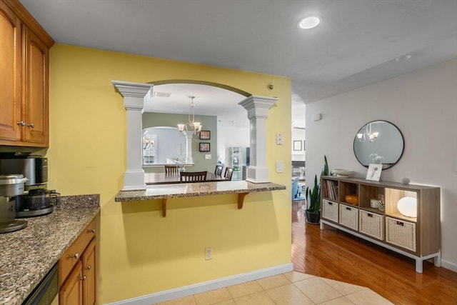 622 Hampton Way Unit 622, Abington, MA 02351 - kitchen featuring decorative columns, a kitchen bar, brown cabinetry, arched walkways, and stone countertops