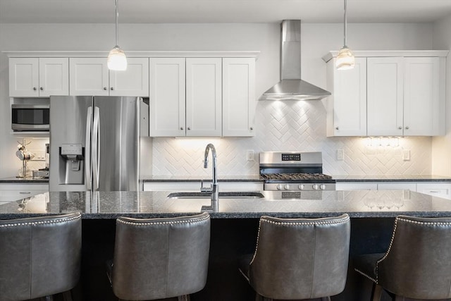 kitchen featuring hanging light fixtures, appliances with stainless steel finishes, decorative backsplash, and wall chimney exhaust hood