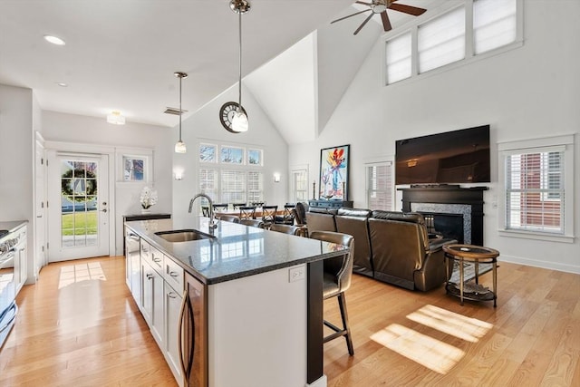kitchen with pendant lighting, a kitchen breakfast bar, ceiling fan, a sink, and light wood-style flooring