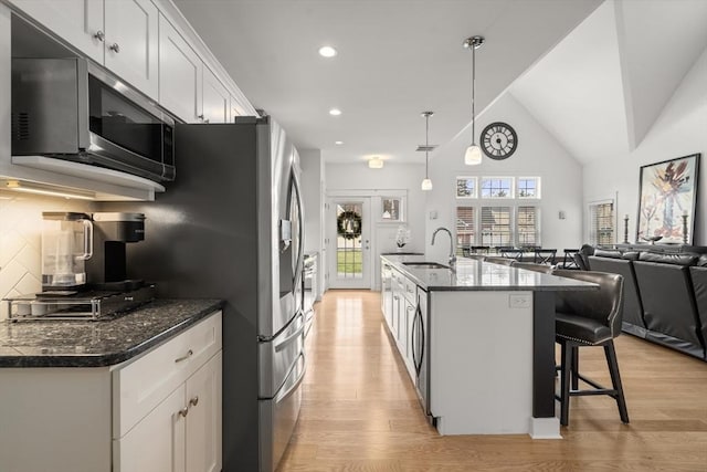 kitchen featuring a breakfast bar area, a sink, light wood finished floors, open floor plan, and stainless steel appliances
