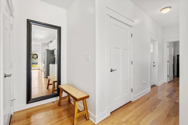 hall with baseboards and light wood finished floors