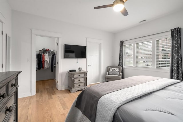 bedroom with a walk in closet, baseboards, light wood-type flooring, visible vents, and a closet