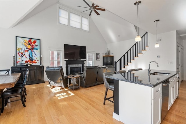 kitchen with white cabinets, ceiling fan, a sink, a kitchen breakfast bar, and high vaulted ceiling
