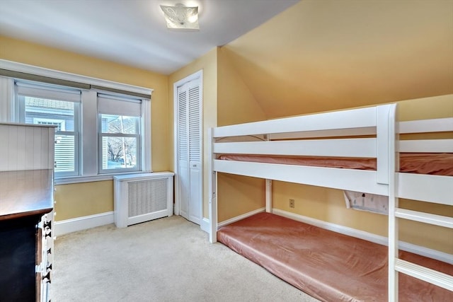 unfurnished bedroom featuring radiator heating unit, light carpet, and a closet