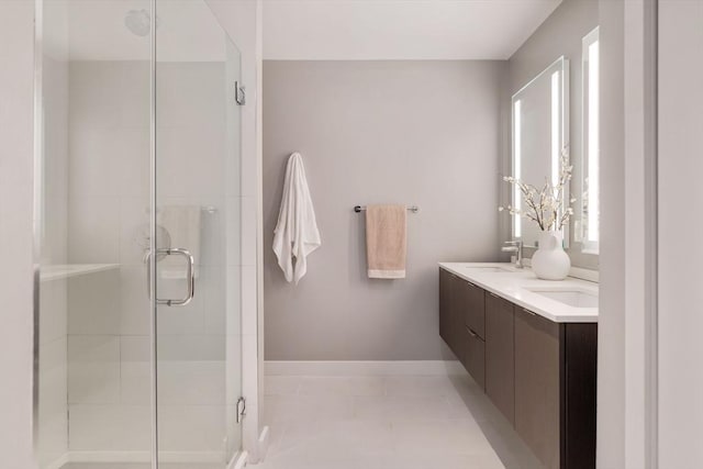 bathroom featuring a stall shower, tile patterned flooring, double vanity, and baseboards