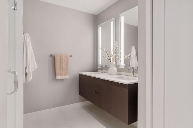 full bath featuring double vanity, baseboards, tile patterned floors, and a shower with door