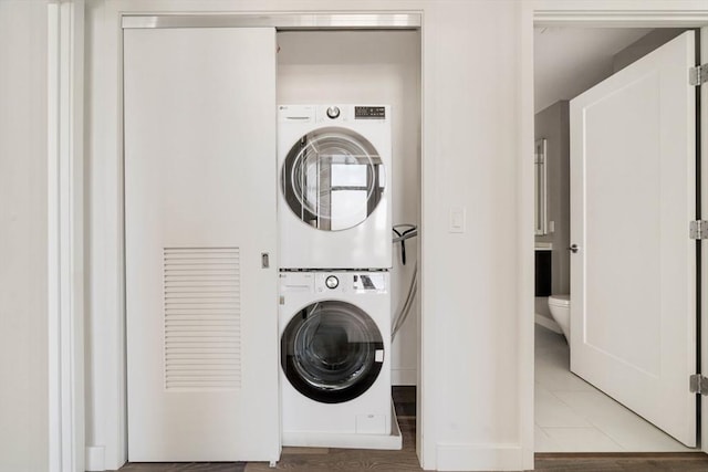 laundry area featuring estacked washer and dryer, baseboards, and light tile patterned floors