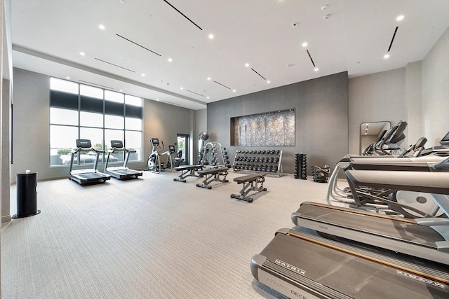 exercise room with carpet floors, a towering ceiling, and recessed lighting