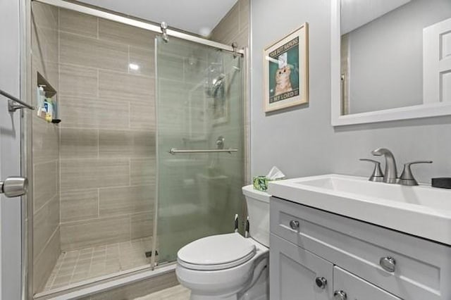 bathroom with a stall shower, toilet, and vanity