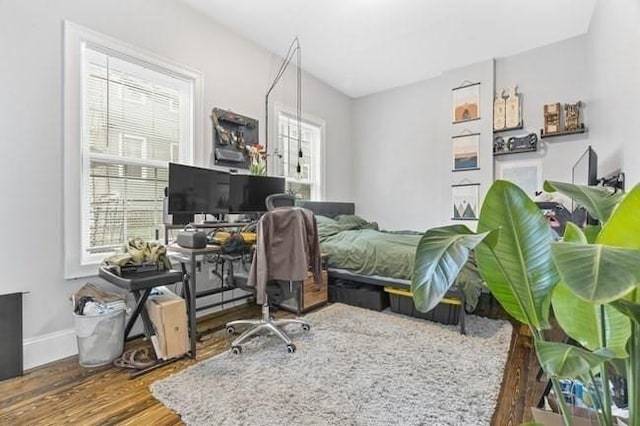 bedroom featuring multiple windows, wood finished floors, a desk, and baseboards