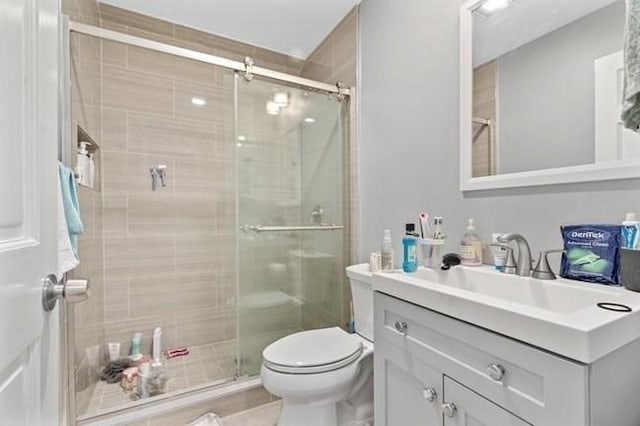 full bath with a stall shower, toilet, and vanity