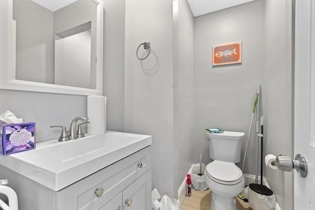 half bath with toilet, vanity, and baseboards