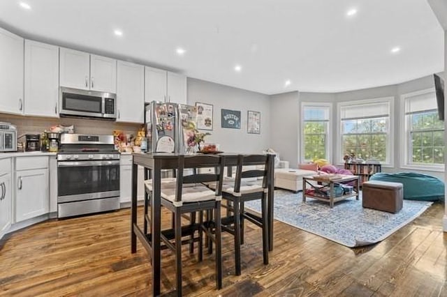 kitchen featuring stainless steel appliances, wood finished floors, recessed lighting, white cabinets, and open floor plan