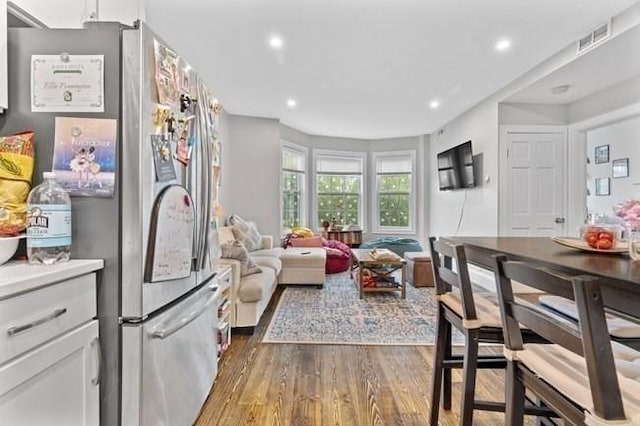 kitchen with freestanding refrigerator, wood finished floors, white cabinets, recessed lighting, and open floor plan
