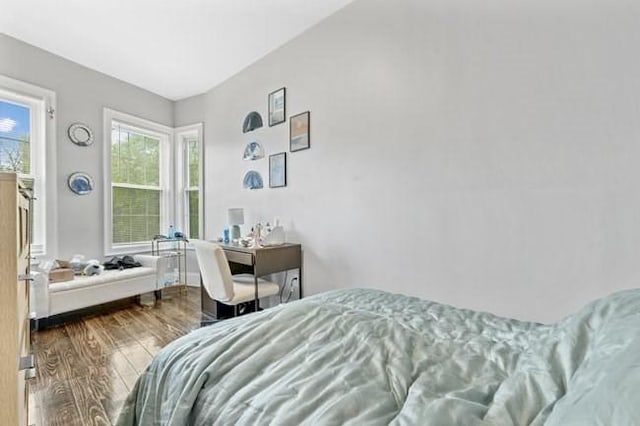 bedroom with wood finished floors and an office area
