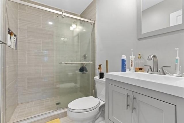 bathroom featuring toilet, a stall shower, and vanity