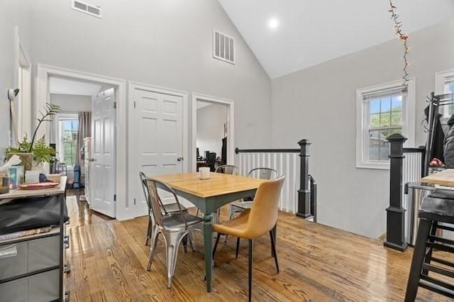 dining area with wood finished floors, high vaulted ceiling, and healthy amount of natural light
