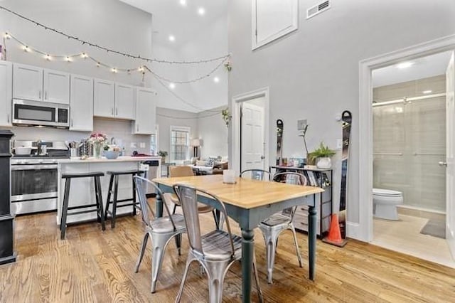 dining room with light wood-style floors and a high ceiling