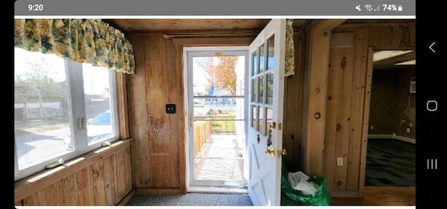 entryway with carpet and wooden walls