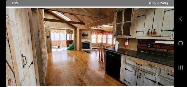 kitchen featuring black dishwasher, lofted ceiling with beams, wood-type flooring, dark stone counters, and wood ceiling