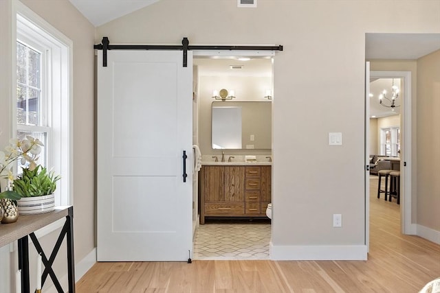 interior space with wood finished floors, visible vents, vanity, vaulted ceiling, and an inviting chandelier