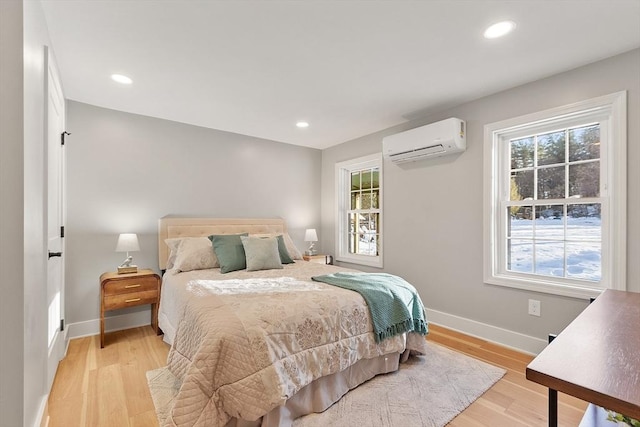 bedroom featuring light wood-type flooring, an AC wall unit, baseboards, and recessed lighting