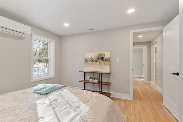 bedroom with light wood-style floors, baseboards, an AC wall unit, and recessed lighting