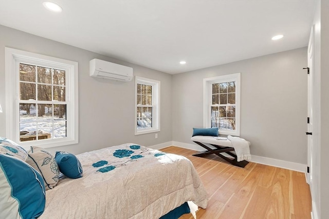 bedroom with light wood-style flooring, baseboards, an AC wall unit, and recessed lighting