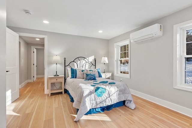 bedroom featuring light wood-style floors, recessed lighting, baseboards, and a wall mounted AC