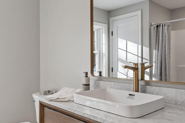 full bath with marble finish floor, a shower with shower curtain, and a sink