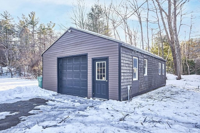 snow covered garage featuring a detached garage