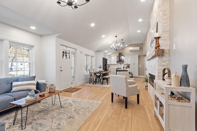 living room featuring baseboards, light wood-style flooring, a fireplace, a chandelier, and recessed lighting