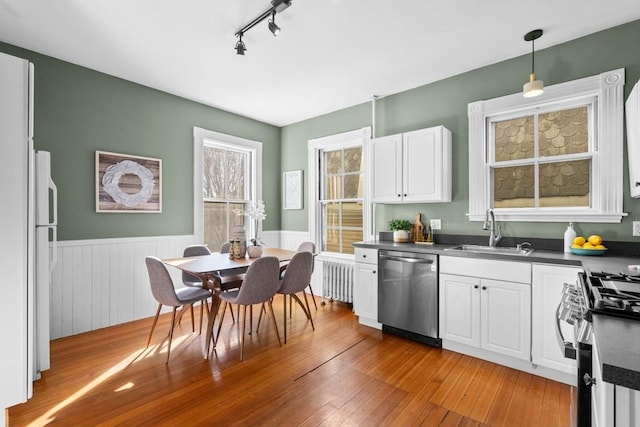 kitchen with stainless steel appliances, white cabinetry, sink, and decorative light fixtures