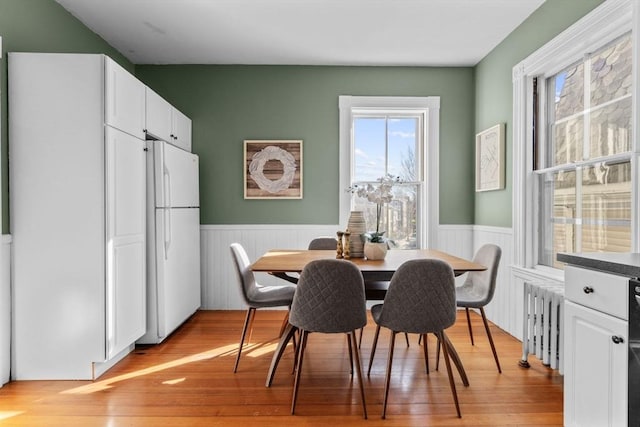 dining space featuring radiator heating unit and light hardwood / wood-style flooring