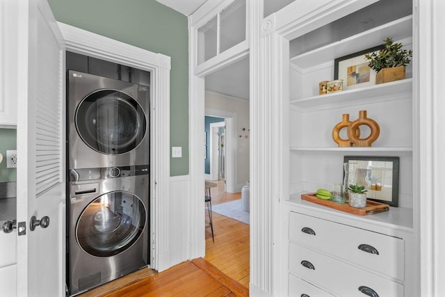 laundry area with stacked washer and clothes dryer, hardwood / wood-style floors, and built in features