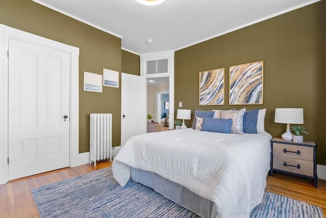 bedroom featuring crown molding, wood-type flooring, and radiator