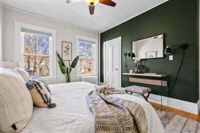 bedroom featuring crown molding, wood-type flooring, radiator, a closet, and ceiling fan