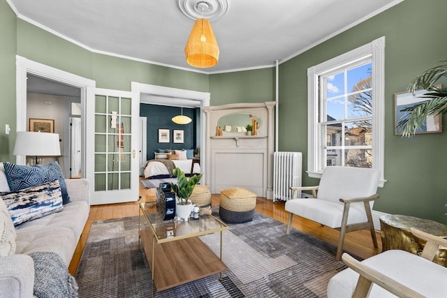 living area featuring hardwood / wood-style flooring, crown molding, radiator heating unit, and french doors