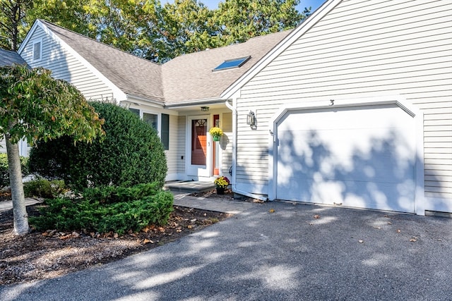 view of front of home featuring a garage, a shingled roof, and aphalt driveway