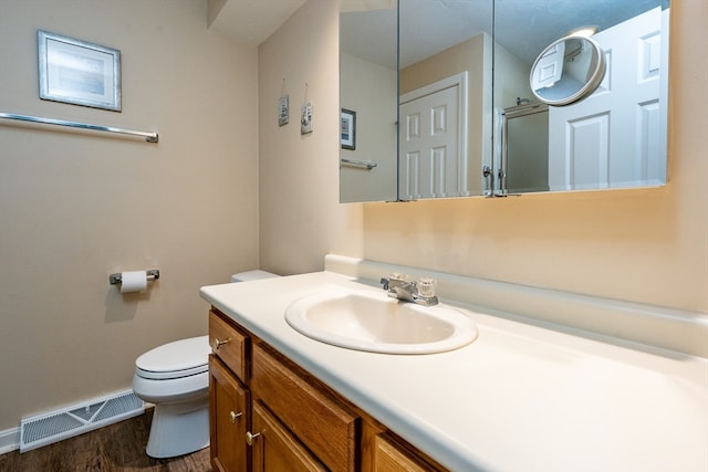 bathroom with baseboards, visible vents, toilet, wood finished floors, and vanity