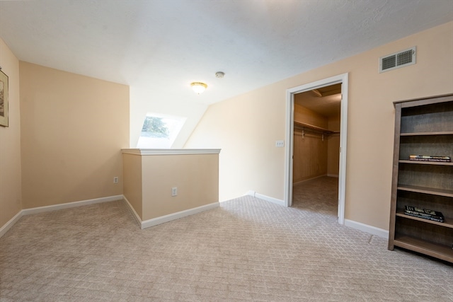 bonus room featuring light colored carpet, visible vents, baseboards, and a skylight