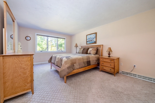 bedroom featuring baseboards, a baseboard heating unit, and light colored carpet