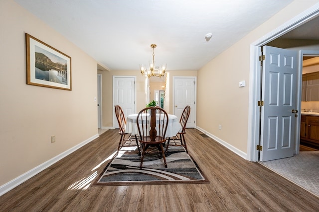 dining space featuring baseboards, dark wood-type flooring, and a notable chandelier